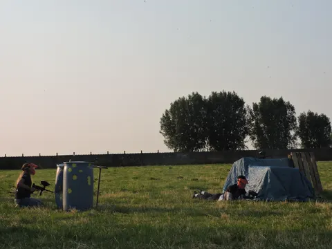 Speler met paintballmarker en masker op het terrein